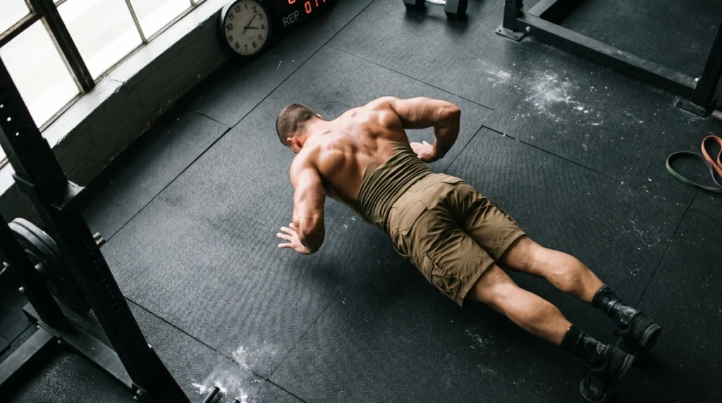 Athlete performing a hand-release push-up during ACFT calisthenics prep training, demonstrating the strict form required for the Army Combat Fitness Test HRP event