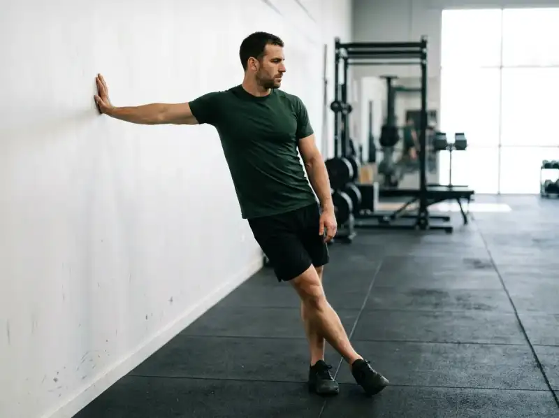 Man performing a standing cross-leg stretch, an effective thigh stretch for the outer thigh and IT band