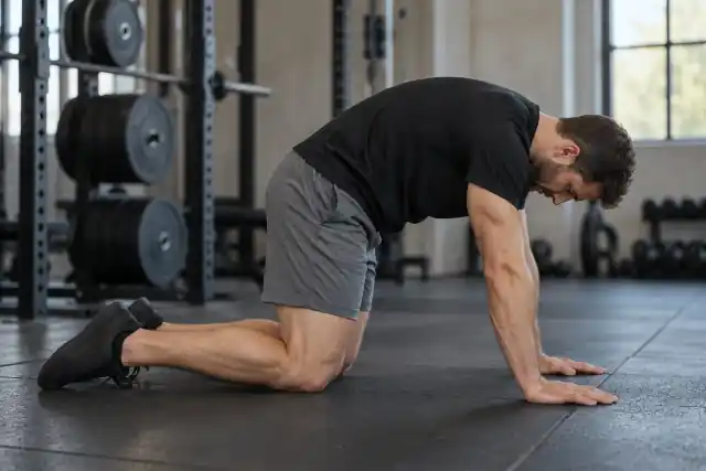 Man in the cat position of a cat-cow stretch on a gym mat – upper body stretches
